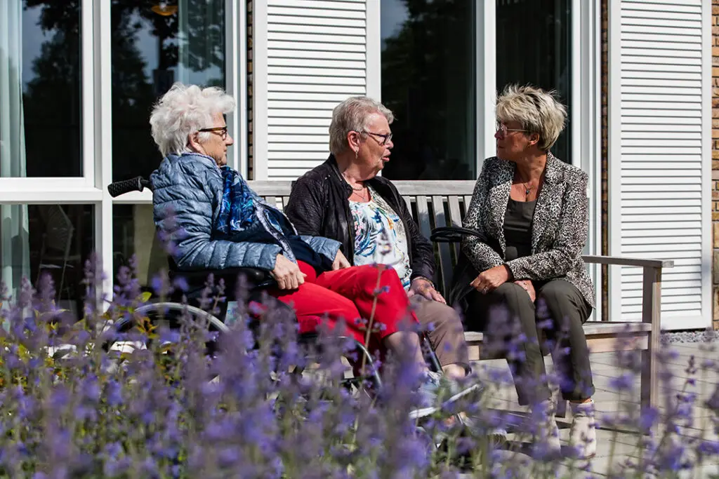 Dinie van Lenthe en haar moeder kletsen samen met een andere bewoonster van Het Vechtdalhuis in Hardenberg buiten op een bankje.