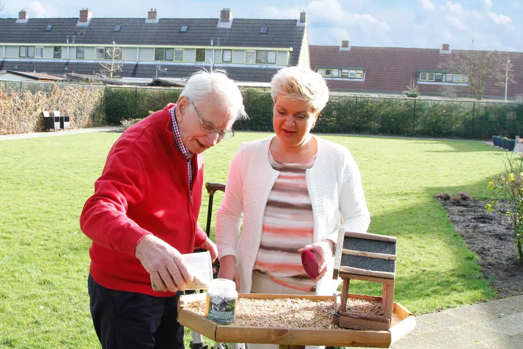 Carmen Willemsen samen met haar vader met dementie in Het Wilderinkhuis in Hengelo waar ze de vogeltjes gaan voeren in de grote tuin.