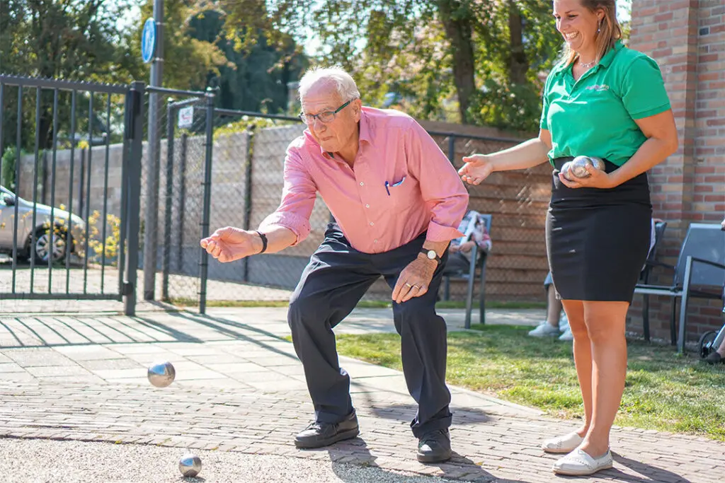 Een bewoner speelt jeu de boules op het terrein van een Dagelijks Leven locatie