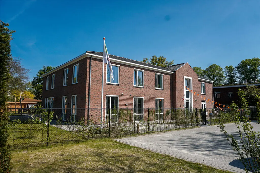 Bewoners wandelen zelfstandig door de open poort naar de buurt, in een veilige, dementievriendelijke omgeving in Ede.