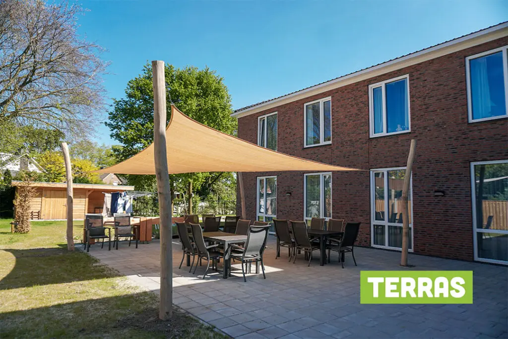 Bewoners wandelen zelfstandig door de open poort naar de tuin in de veilige, dementievriendelijke omgeving van Het Kraatshuis in Ede.