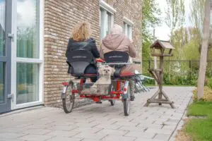 Foto genomen terwijl moeder en dochter samen wegfietsen met het hondje achterop. 