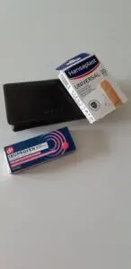 Foto van een portemonnee met een pakje ibuprofen en pleisters ernaast. Ter illustratie bij een anekdote over een dame met pijn in haar portemonnee.