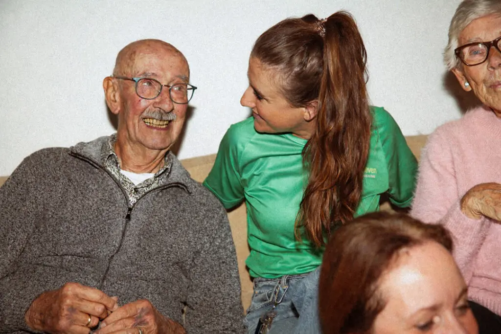 Twee medewerkers van Dagelijks Leven poseren voor de campagne "Lekker met de meiden" samen met twee bewoners met dementie. De medewerkers zijn verpleegkundige, verzorgende ig of helpende