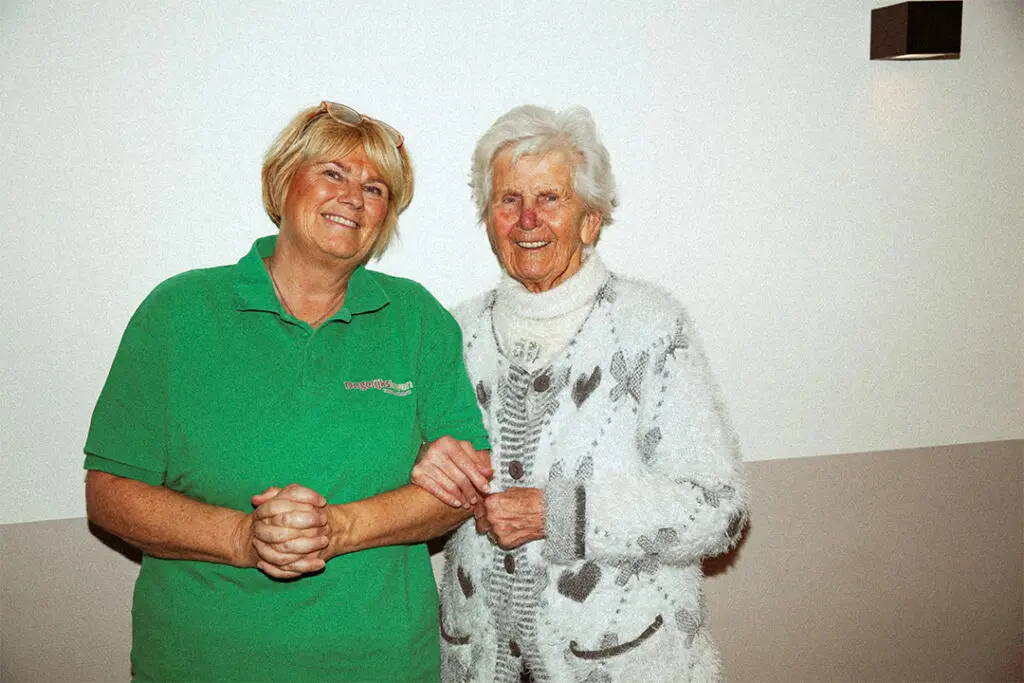 Een medewerkster van Dagelijks Leven poseert voor de campagne "Lekker met de meiden" samen met twee bewoners met dementie. De medewerkster is verpleegkundige, verzorgende ig of helpende