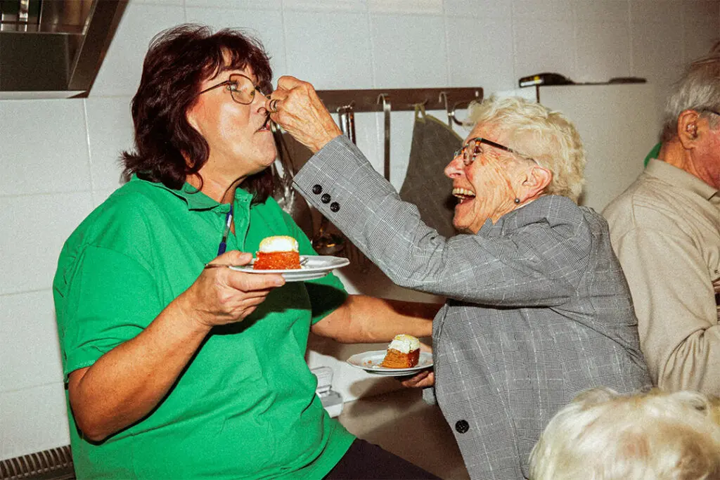 Twee medewerkers van Dagelijks Leven poseren voor de campagne "Lekker met de meiden" samen met twee bewoners met dementie. De medewerkers zijn verpleegkundige, verzorgende ig of helpende