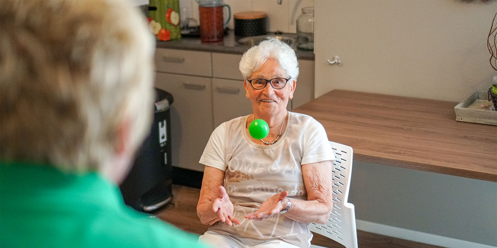 een mevrouw met dementie doet lichaamsactiviteiten met een medewerker van Dagelijks Leven.