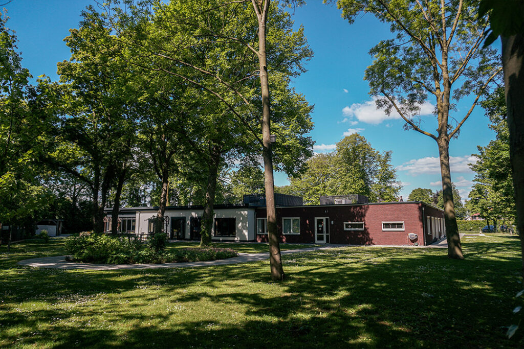 Bewoners wandelen zelfstandig door de open poort naar de grote tuin in de veilige, dementievriendelijke omgeving van Het Jasmijnhuis aan de Jasmijnstraat in Ridderkerk.