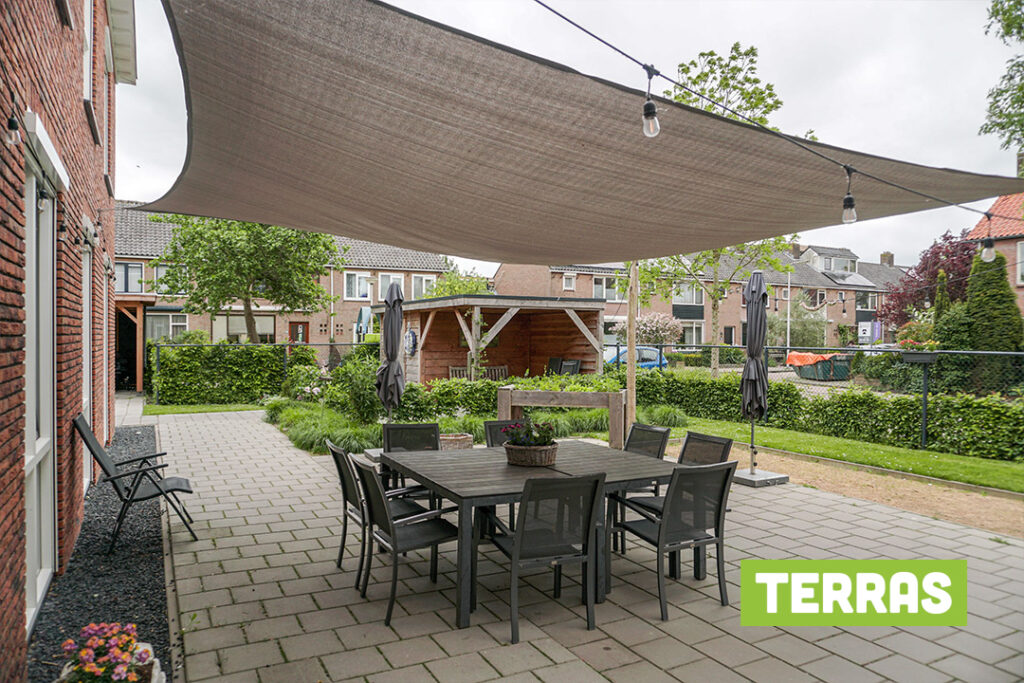 Het terras van Het Vlisthuis met schaduwdoek voor bewoners met dementie in Schoonhoven