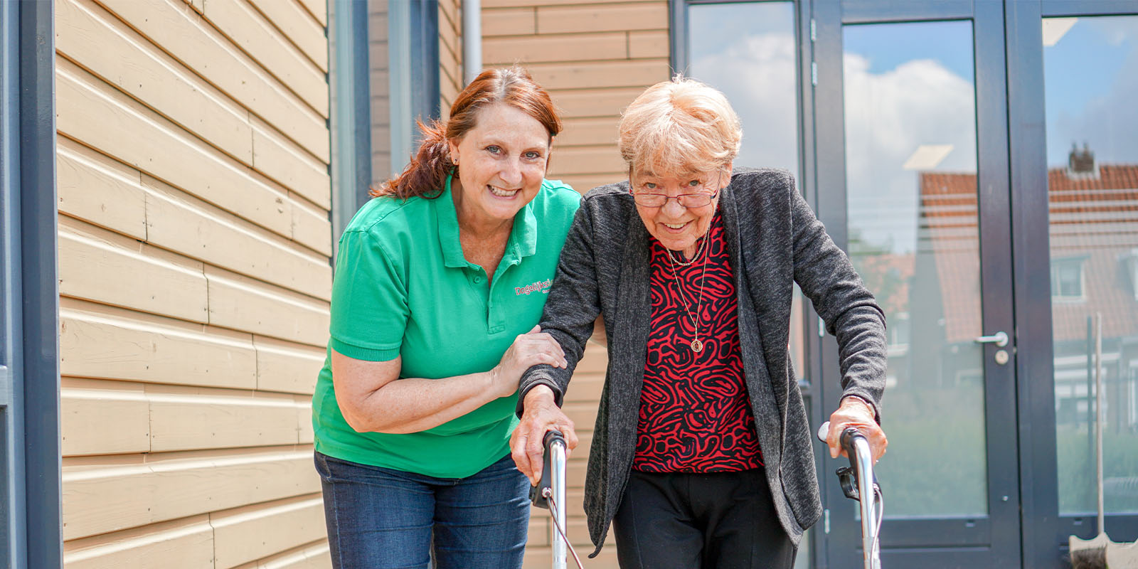 Een medewerker van Dagelijks Leven helpt een bewoner met dementie wandelen, lees hierover meer in onze informatiebrochures.