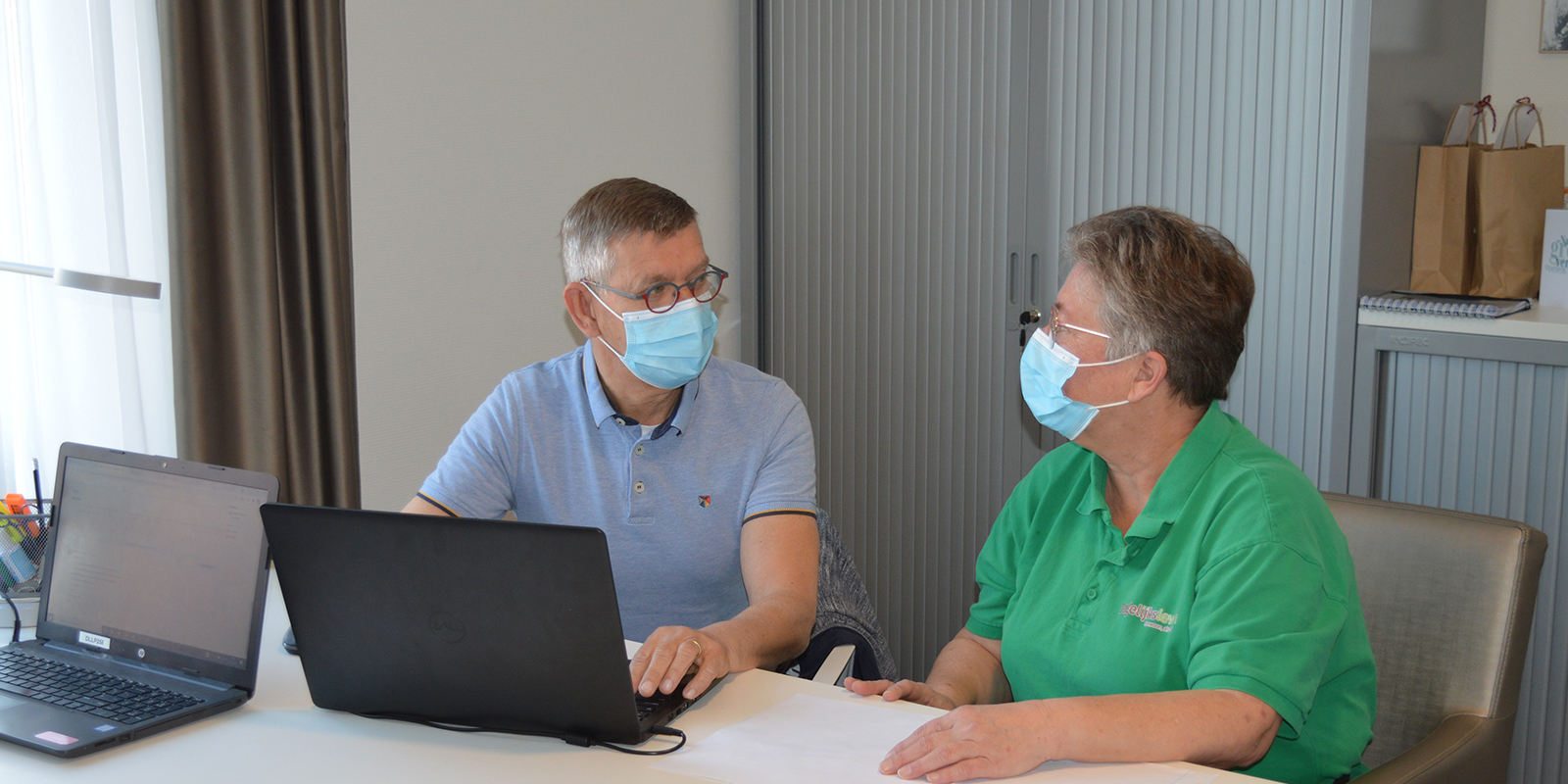 Verpleegkundig specialist Willy Erdhuizen in gesprek met een zorgmedewerker, samen aan een bureau achter een laptop