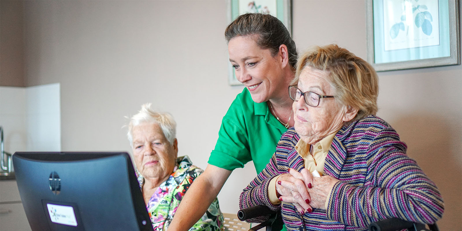 Bewoners van Dagelijks Leven kijken samen met een zorgmedewerker naar de CAO VVT 2023 op een laptop