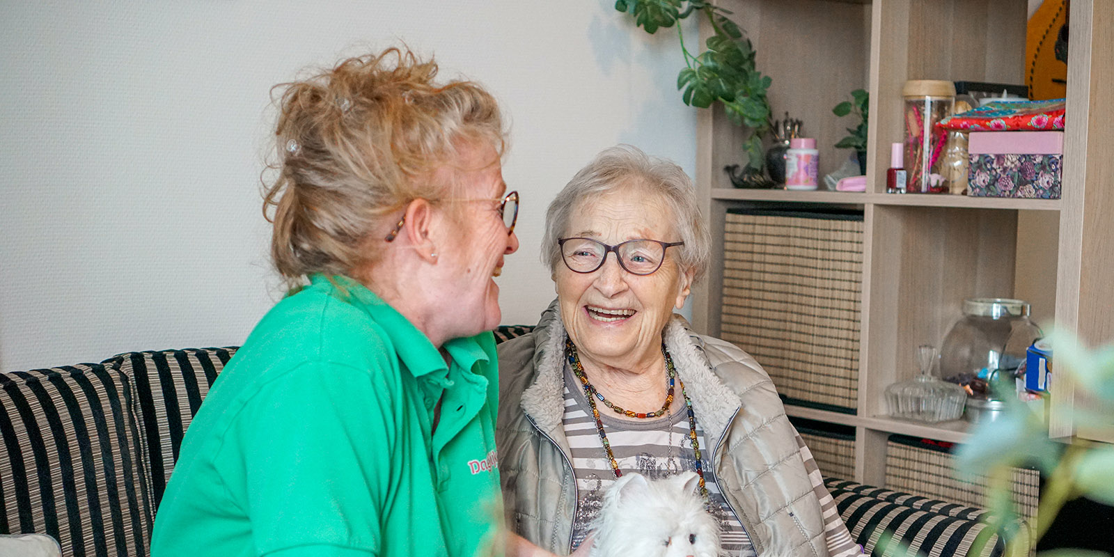 Een zorgmedewerker van Dagelijks Leven knuffelt een bewoner van een woonzorglocatie voor mensen met dementie.