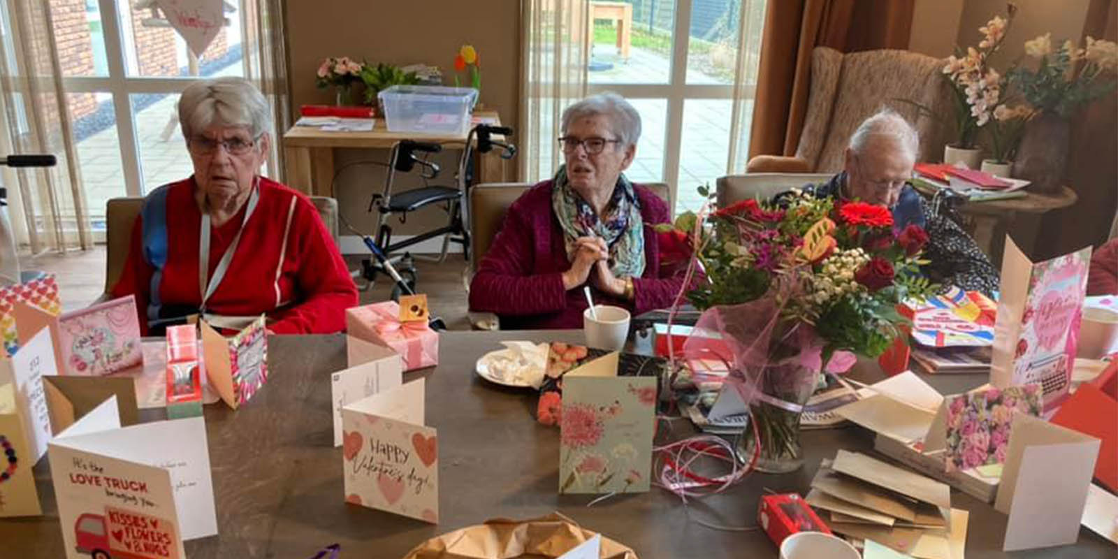 De bewoners van Het Oosterhuis in Oosterwolde aan een tafel vol valentijnskaarten.