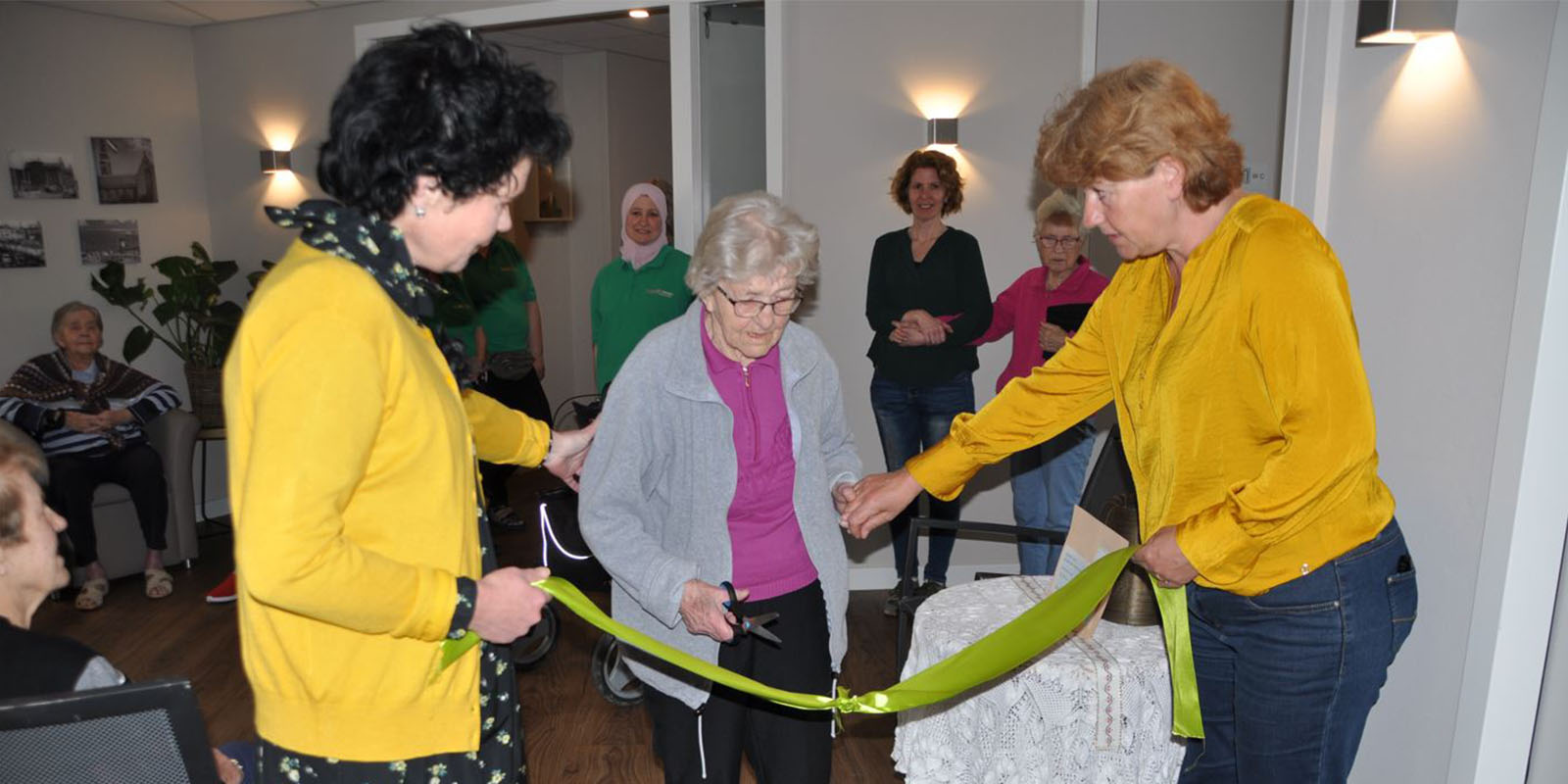 Bewoonster van Het Hyacintenhuis in Vlissingen knipt een groen lint door, en opent zo haar eigen expositie in de kleinschalige zorglocatie voor mensen met dementie.
