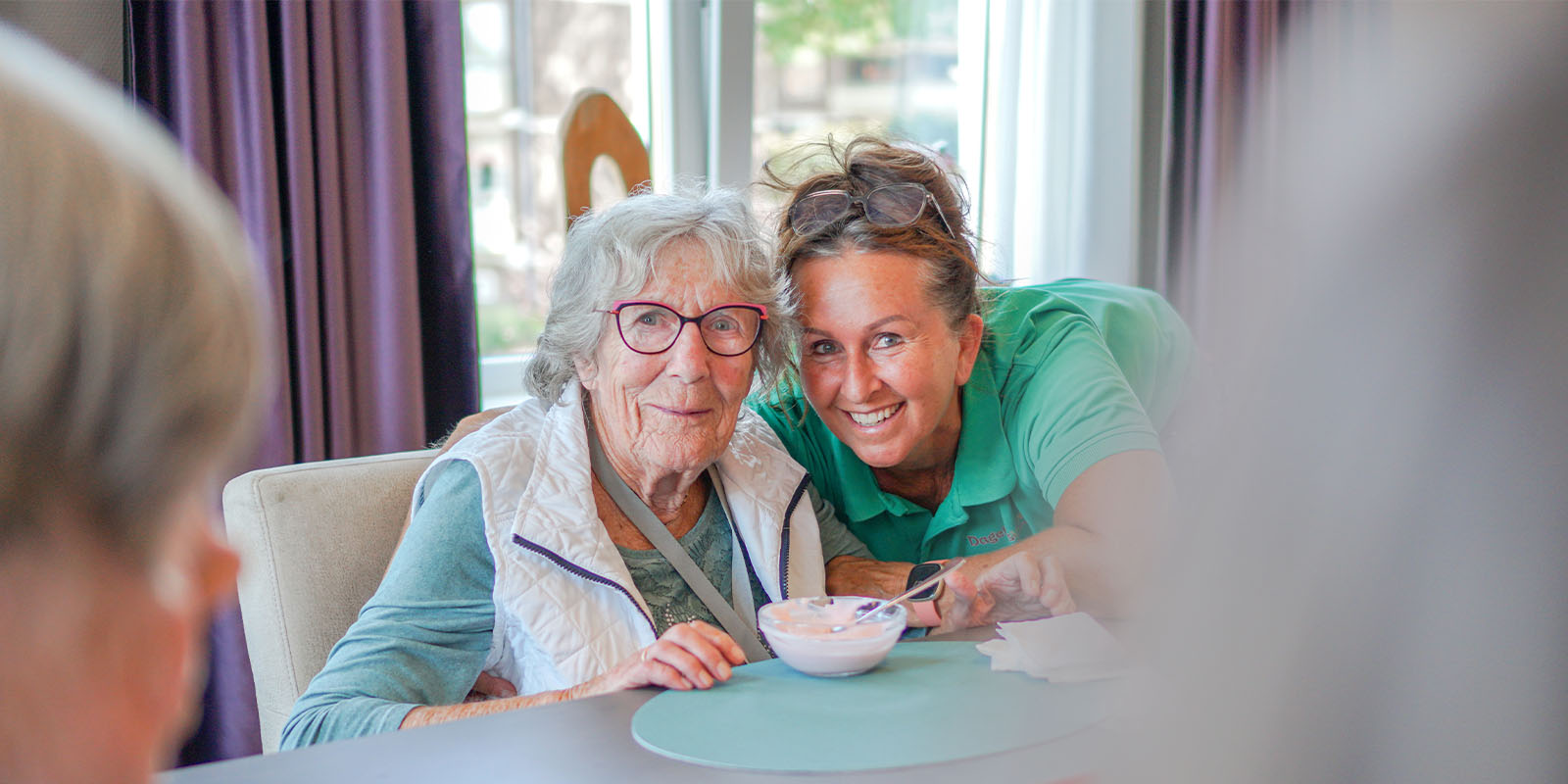 Een bewoonster met dementie bij Dagelijks Leven drinkt thee aan de keukentafel, gewoon als thuis.