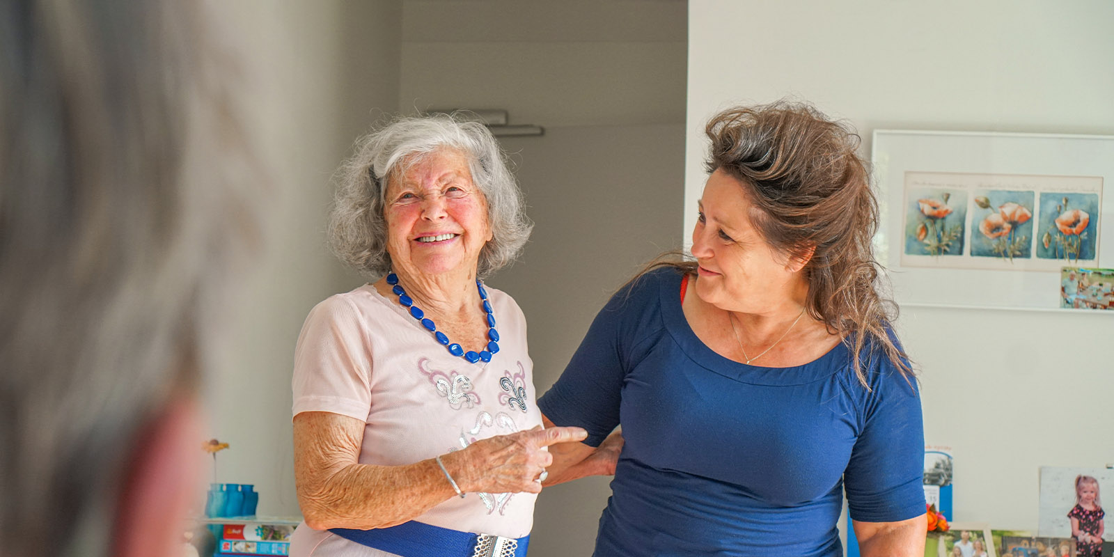 Verpleegkundig specialist samen met een bewoner met dementie op een woonzorglocatie van Dagelijks Leven. Ze lachen naar elkaar.