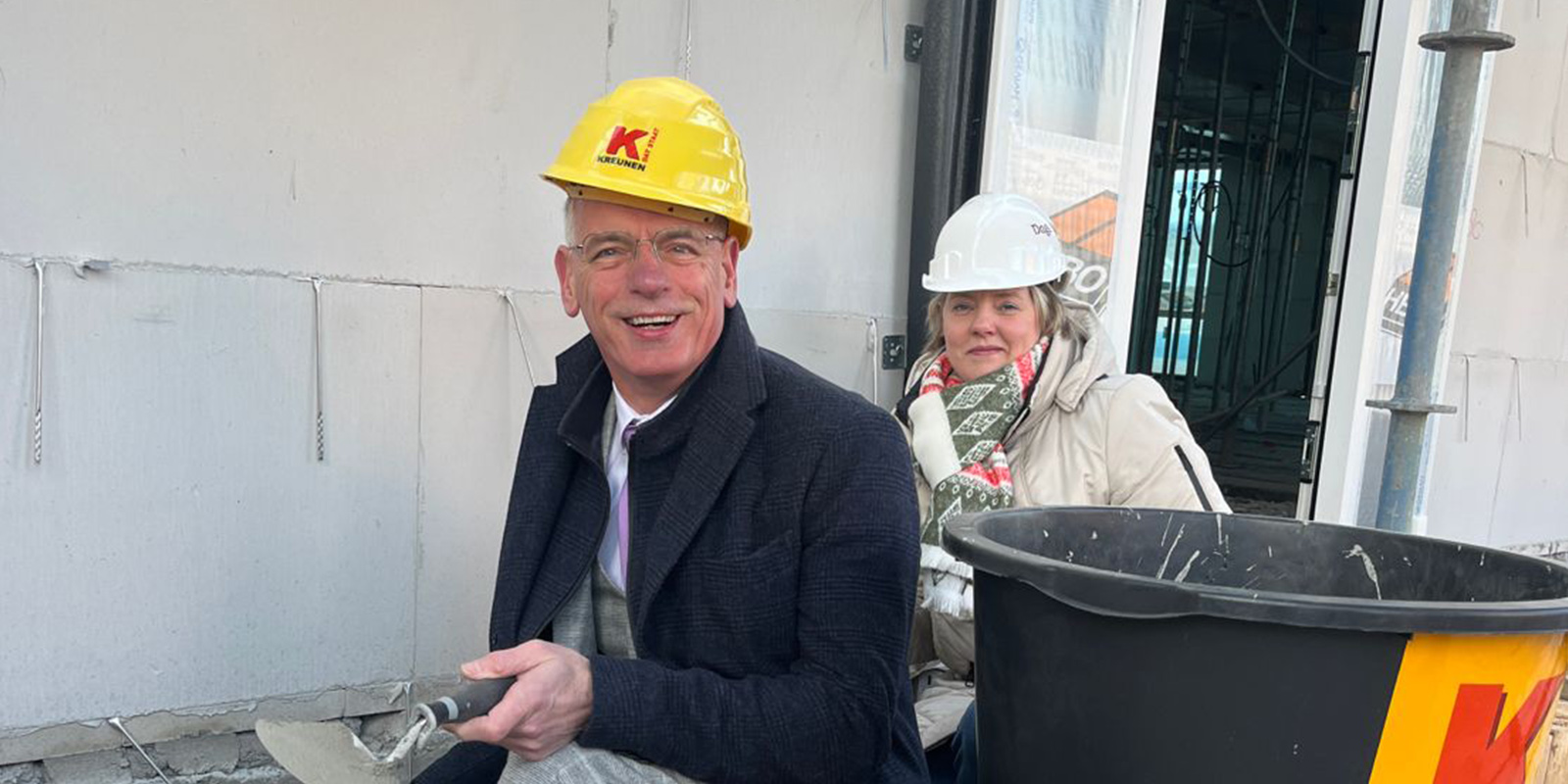 Wethouder en locatiemanager metselen samen de eerste steen van Het Looleehuis, de kleinschalige woonzorglocatie voor mensen met dementie in Almelo.