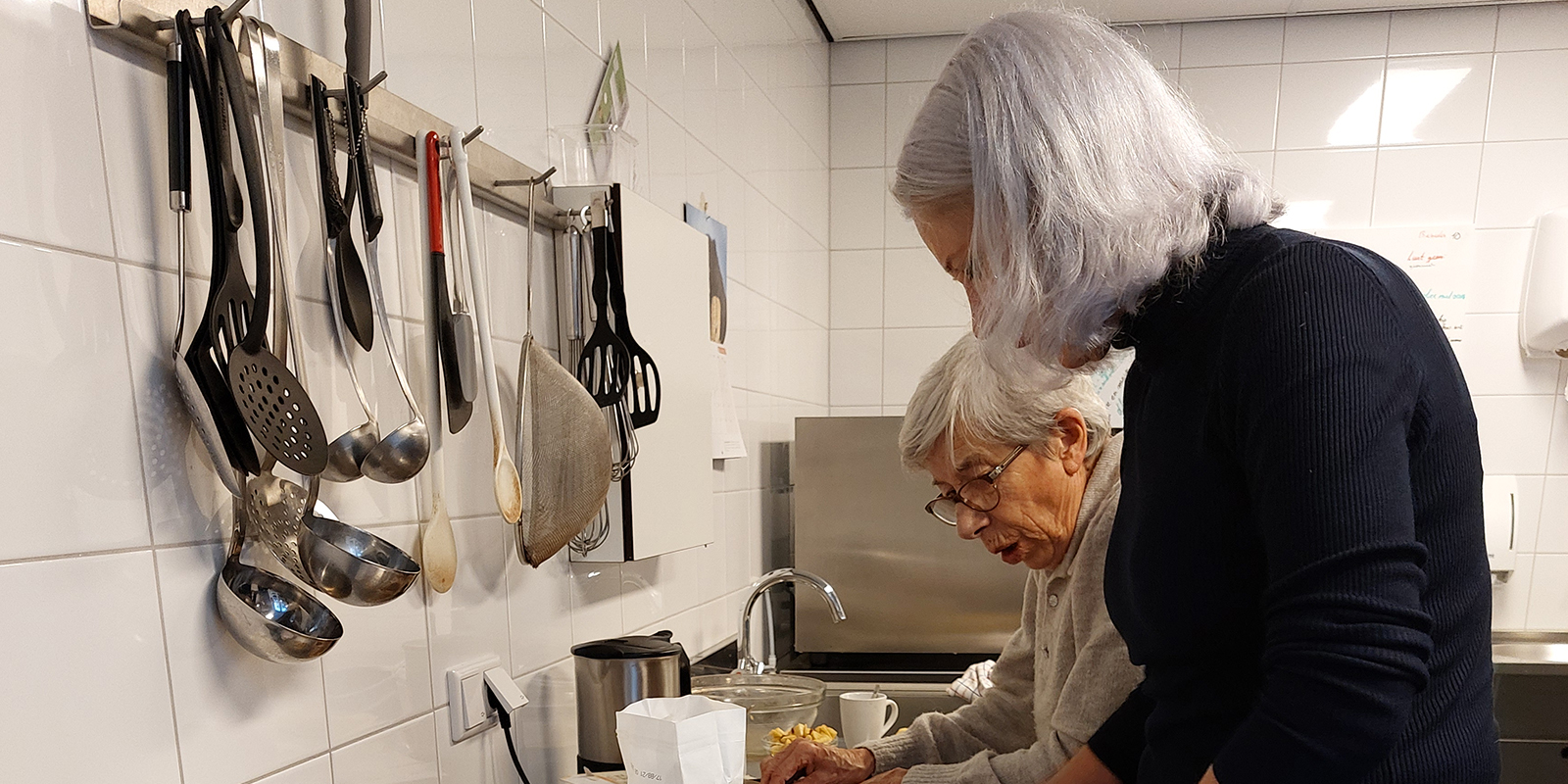 Een bewoonster met dementie samen met haar dochter in de keuken. Ze bakken een appeltaart. Net als vroeger.
