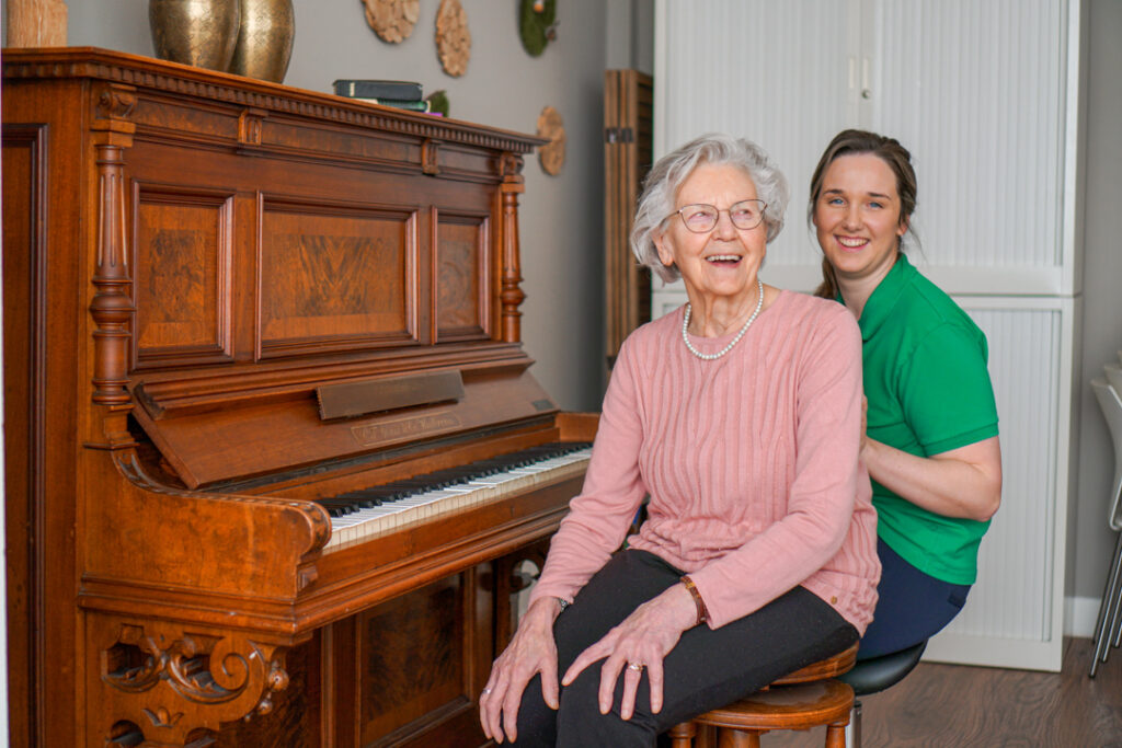 Een bewoonster met de ziekte van Alzheimer speelt graag piano samen met een zorgmedewerker in het verpleeghuis van Dagelijks Leven voor mensen met dementie