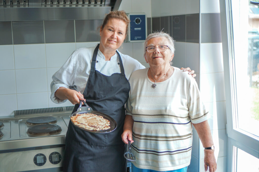Een bewoonster met alzheimer helpt de kok met het koken van pannenkoeken in de kleinschalige zorglocatie voor mensen met dementie van Dagelijks Leven