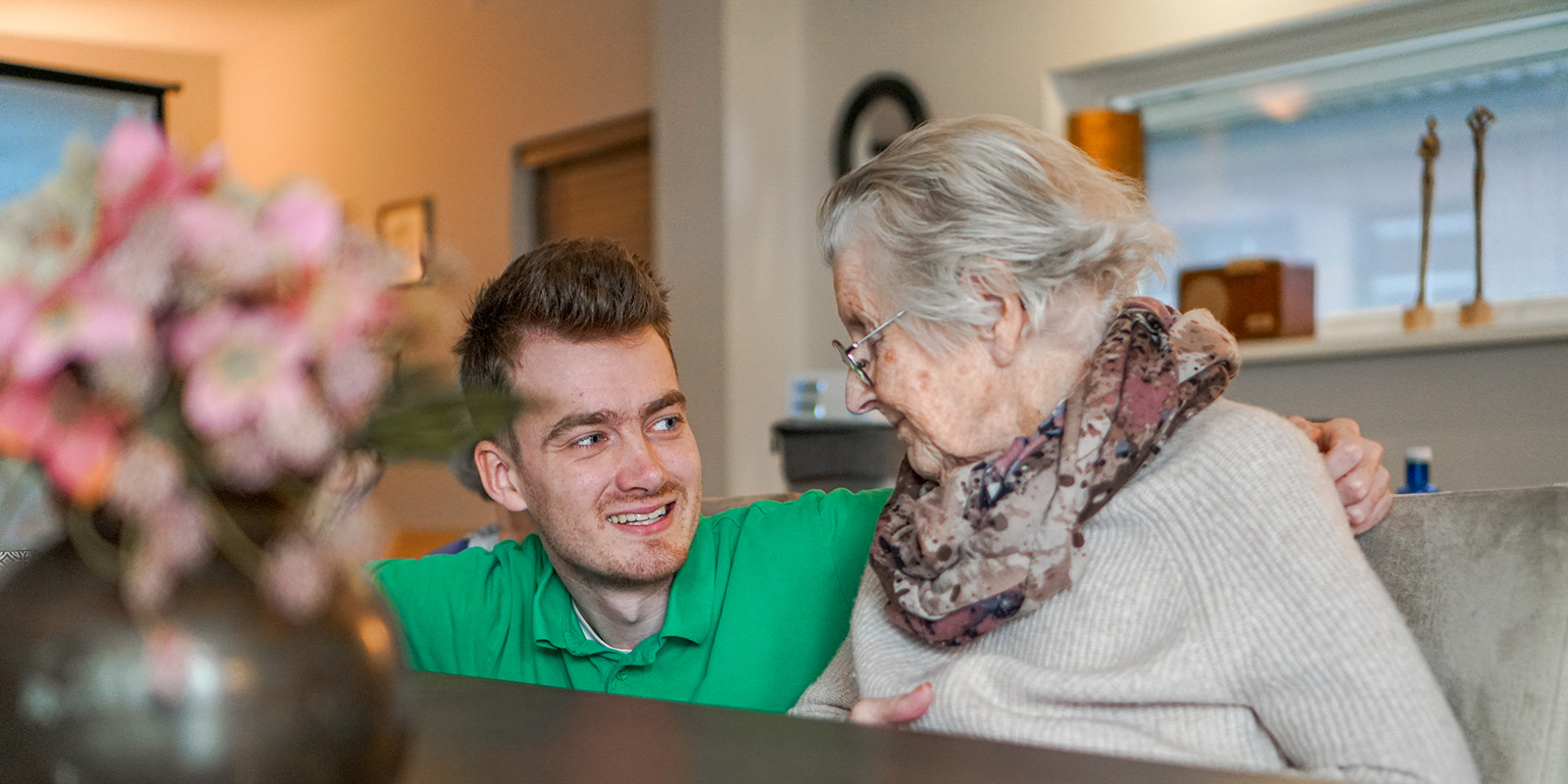 Een bewoner en een medewerker zitten samen aan tafel in een kleinschalige woonzorglocatie voor mensen met dementie in Emmen.