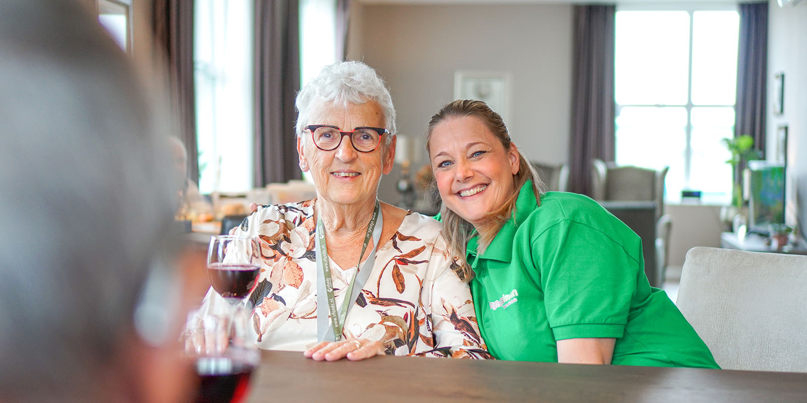 Sfeerimpressie van bewoner en medewerker die genieten van een heerlijk glas wijn