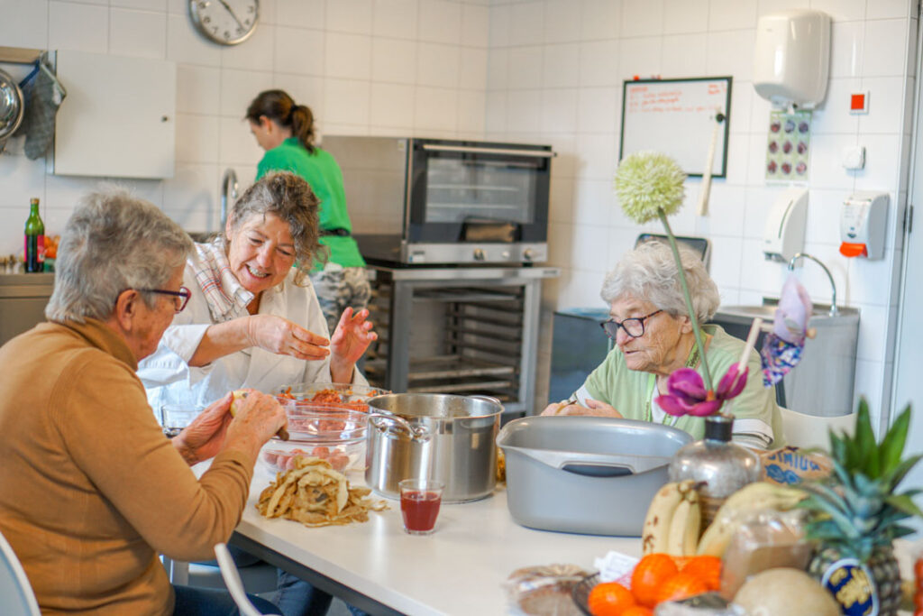 Bewoonsters met dementie helpen de kok met koken in de in de kleinschalige woonzorglocatie van Dagelijks Leven