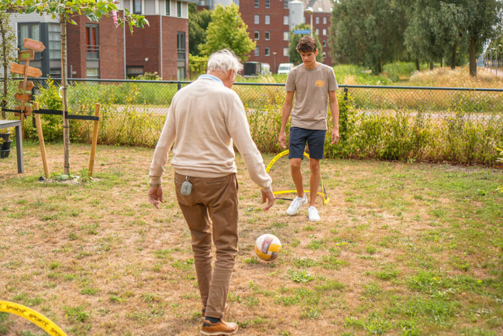 Een bewoner van de woonzorglocatie van Dagelijks Leven voor mensen met dementie voetbalt met een vrijwilliger