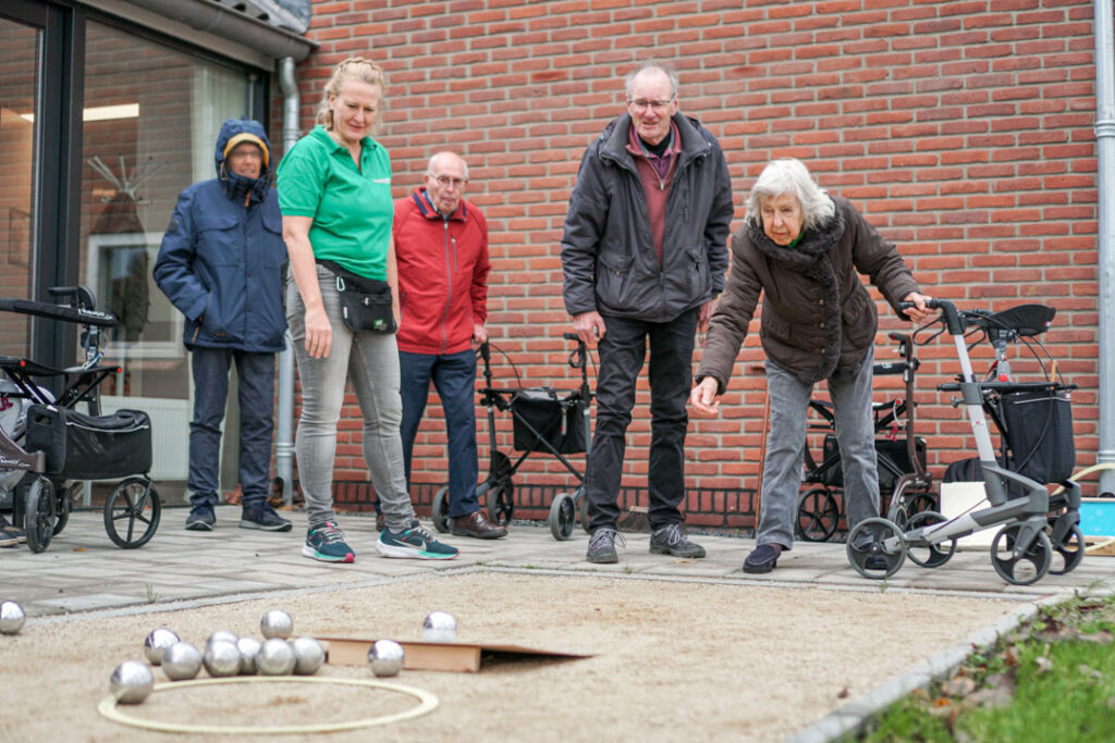 Bewoners van de woonzorglocatie van Dagelijks Leven voor mensen met dementie spelen met elkaar jeu de boules op de jeu de boules-baan die bij de locatie ligt