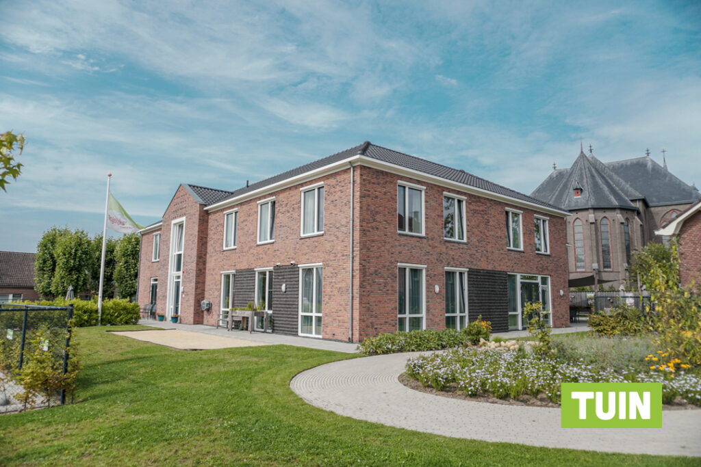 De tuin van Het Carmelhuis, met op de achtergrond een mooie kerk in Oldenzaal