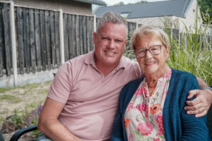 Bewoonster van Het Alterehuis samen met haar zoon in de tuin van de kleinschalige woonzorglocatie voor mensen met dementie. 